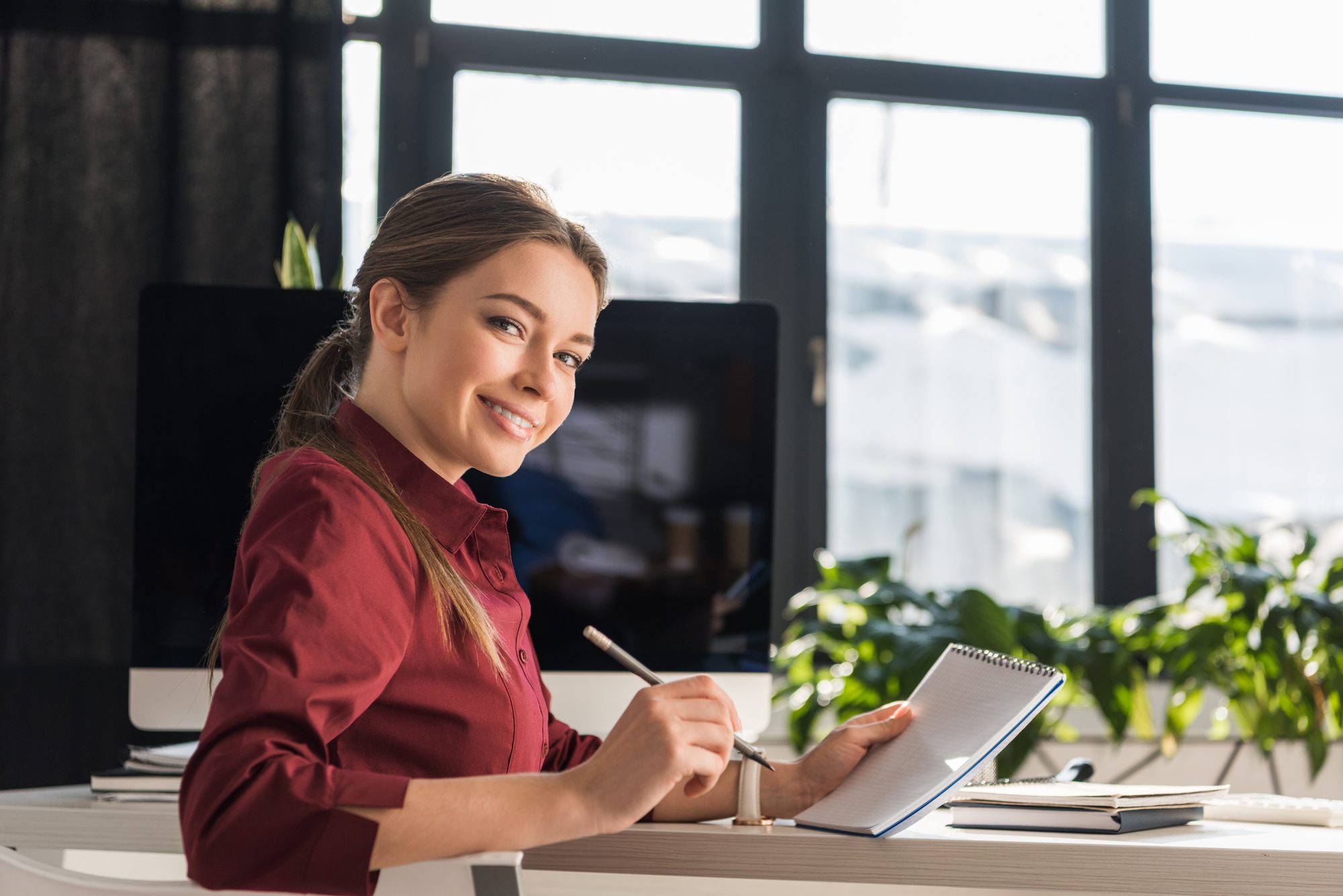 Portrait of female office working smiling while writing